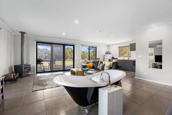 A modern bathroom with a freestanding bathtub, a large window, and a view of the outdoors.