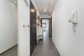 Ein Flur mit Telefon an der Wand, einer Tür und einem Metallregal.
