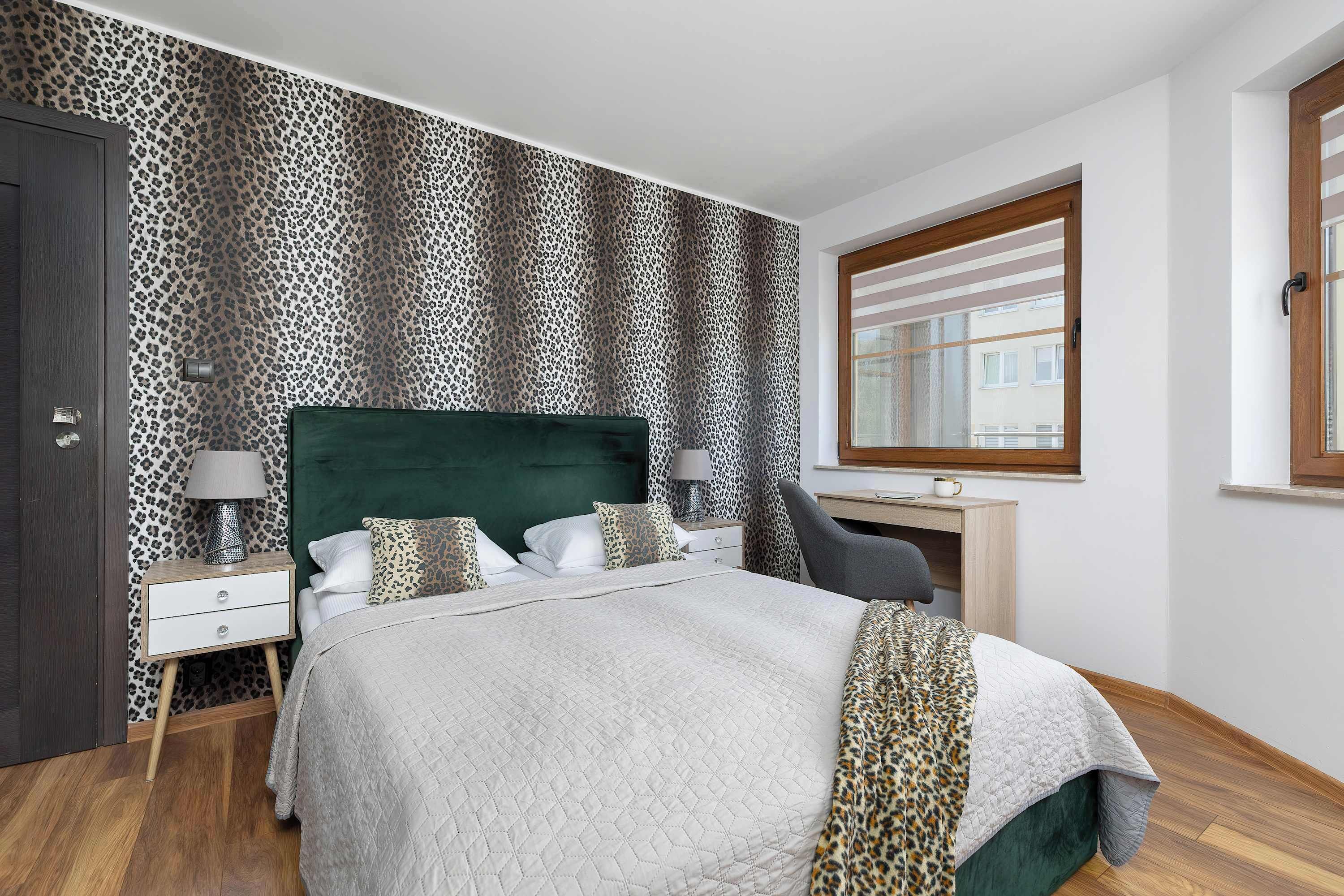 Quarto com cama, mesa de cabeceira, escrivaninha e janela.