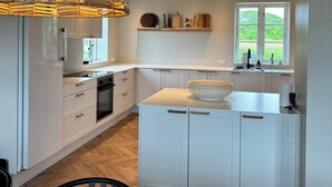 Een moderne keuken met witte kasten, een centraal eiland en een hangende lamp.