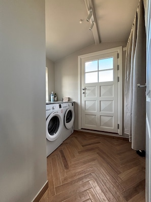 Une buanderie Ă©quipĂ©e dâun lave-linge, dâun sĂšche-linge et dâune porte avec une fenĂȘtre.