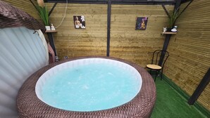 A hot tub with a wicker exterior, surrounded by a wooden wall and artificial grass. - The Mongolian Yurt, an unusual accommodation (Souleuvre en Bocage)