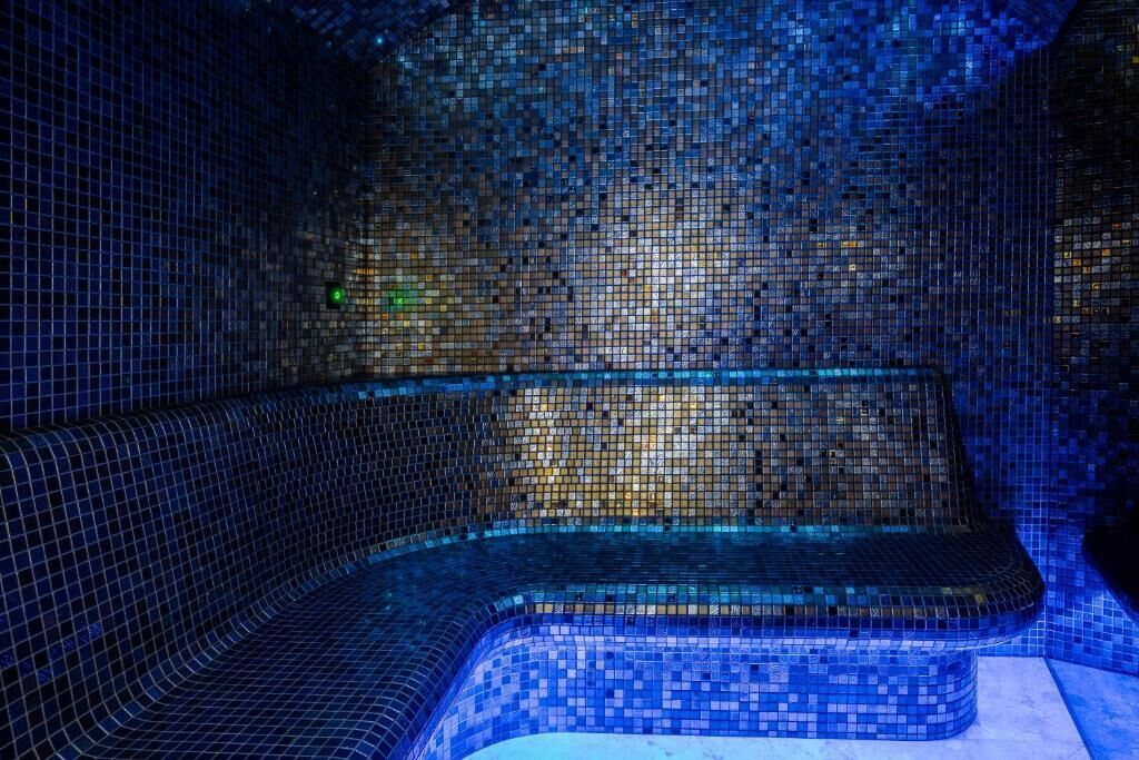 Una habitación con paredes revestidas de mosaicos y un banco curvo.