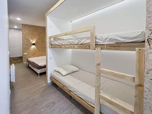 A bunk bed with a mattress and pillows, a wooden floor, and a wall with a textured pattern. - House Floëge 4 persons (Burzet)