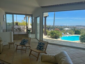 A spacious room with a large sliding glass door leading to a balcony with a pool and city views. - Magnificent sea view villa (Vallauris)