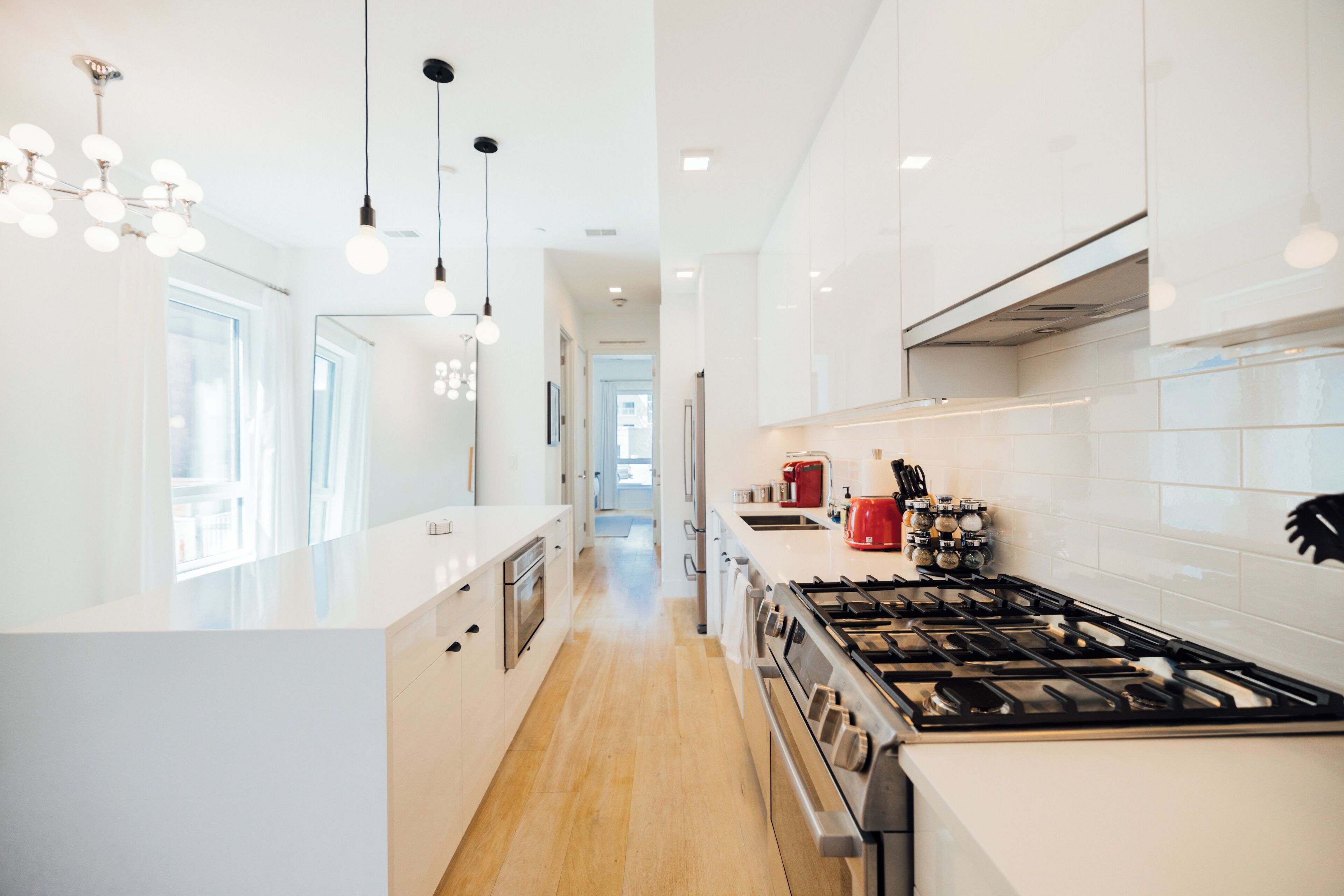 A modern kitchen with white cabinetry, a stainless steel stove, and pendant lighting.
