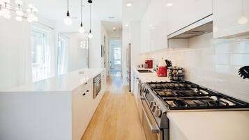A modern kitchen with white cabinetry, a stainless steel stove, and pendant lighting.