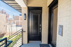 A black door with a keypad lock, a mailbox, and a metal railing on a balcony. - "Second Best" Condo with King Bed in the Heart of Brush Park (Detroit)