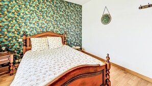 Ein Schlafzimmer mit Wandmuster, einem hölzernen Bett, einem Nachttisch und einer Wandleuchte.