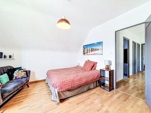 A bedroom with a bed, a sofa, a mirror, and a picture on the wall. - Maison Le Guerno by Interhome (Le Guerno)