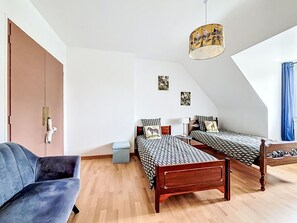 Ein Schlafzimmer mit zwei Betten, einem Schlafsofa, einem kleinen Tisch und einer Pendelleuchte.