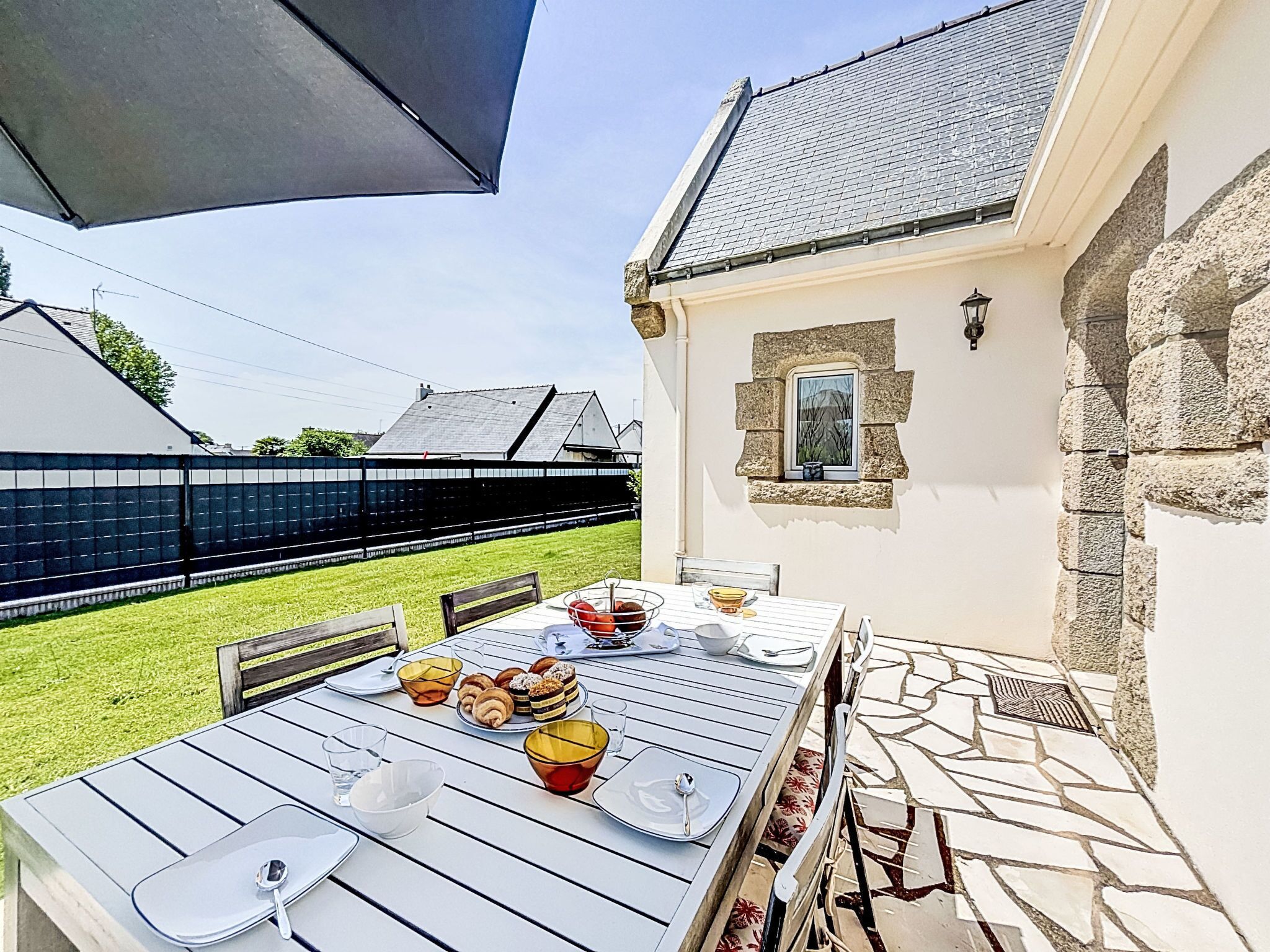 Ein Essbereich im Freien mit einem Tisch für vier Personen, umgeben von Steinmauern und einer überdachten Terrasse.