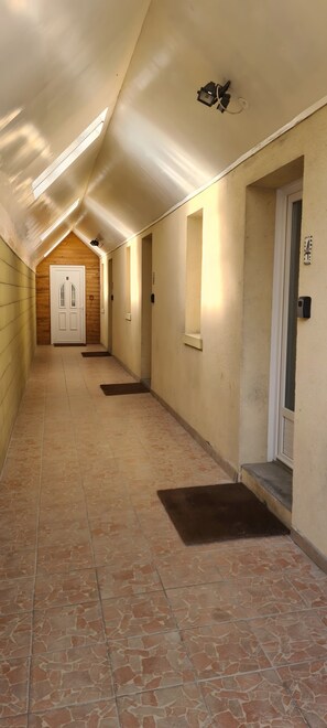 Un couloir avec un plafond en pente, une porte en bois au fond et une petite fenĂȘtre.