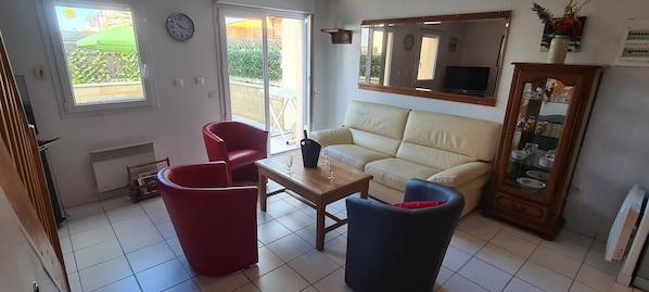 Un salon comprenant un canapé, deux fauteuils, une table basse, un téléviseur et un meuble.