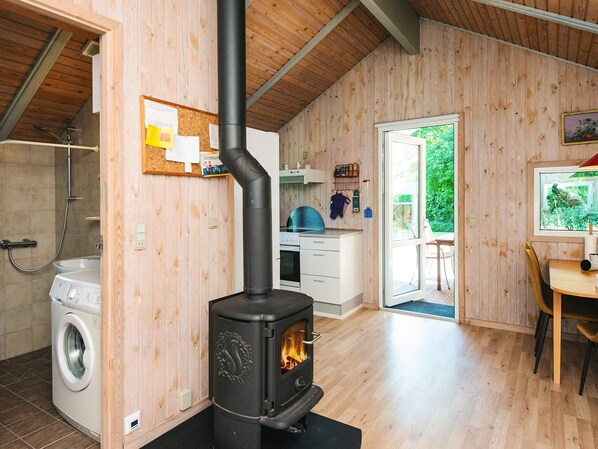 Eine kompakte Küche mit Holzofen, Waschmaschine und Essbereich mit Blick ins Freie.