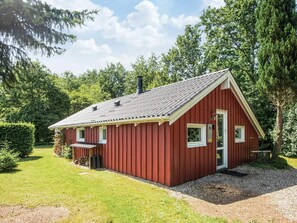 A red wooden cabin with a sloped roof, a small porch, and a gravel driveway. - 4 Star Holiday Home in Hovborg (Hovborg)