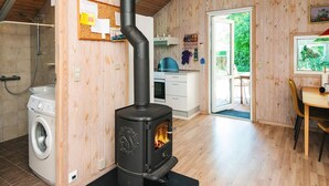 A kitchen with a wood-burning stove, a washing machine, and a dining area with a view of greenery. - 4 Star Holiday Home in Hovborg (Hovborg)