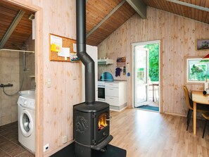 A kitchen with a wood-burning stove, a washing machine, and a dining area with a view of greenery. - 4 Star Holiday Home in Hovborg (Hovborg)