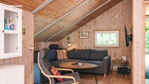 A cozy loft-style room with a wooden ceiling, a gray sofa, a wooden coffee table, and a small side table. - 4 Star Holiday Home in Hovborg (Hovborg)