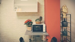 A small kitchenette with a microwave, a potted plant, and a shelf with decorative items.