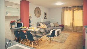 A compact living space with a dining area, a sofa, and a kitchen area.