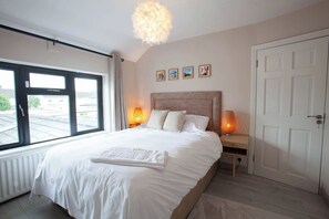 A bedroom with a large bed, two bedside lamps, a window, and a door. - Modern 3BDR Home w Garden (Dublin)