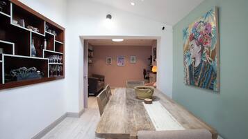 A dining area with a wooden table, chairs, a vase, and a painting on the wall.