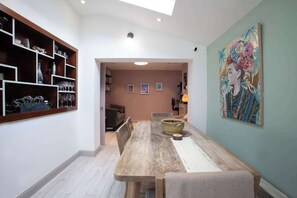 A dining area with a wooden table, chairs, and a vase. There is a bookshelf with various items and a painting on the wall. - Modern 3BDR Home w Garden (Dublin)