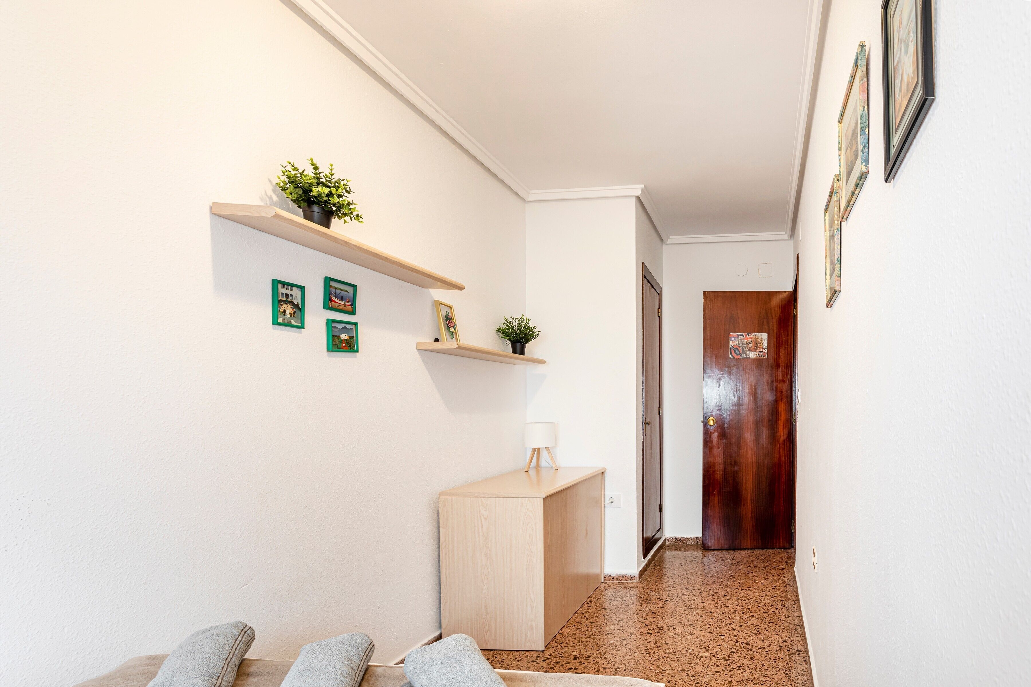 A hallway with a wooden bench, a small table with a lamp, and a door at the end.