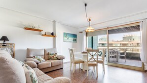 A living room with a sofa, chairs, a dining table, and a view through a sliding glass door.