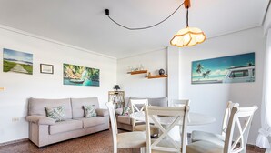 A living room with a sofa, chairs, a table, and wall art.