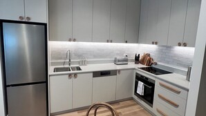 Eine moderne Küche mit Edelstahlgeräten, weißen Schränken und einem Holztisch.