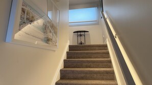 Eine Teppichstufen-Treppe mit Handlauf, einem Oberlicht und gerahmten Kunstwerken an den Wänden.