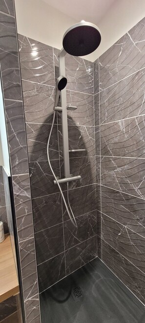 A shower with a curved design, a handrail, and a control panel.