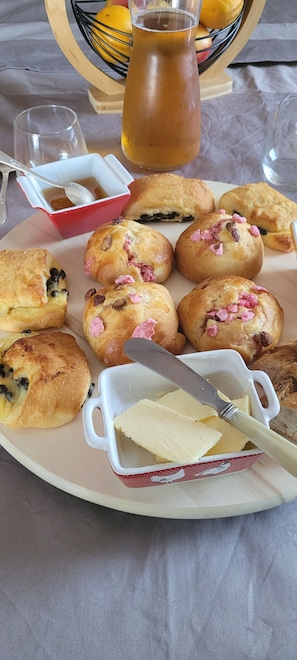 Una bandeja de desayuno con muffins, un recipiente con mantequilla y una jarrón de té.