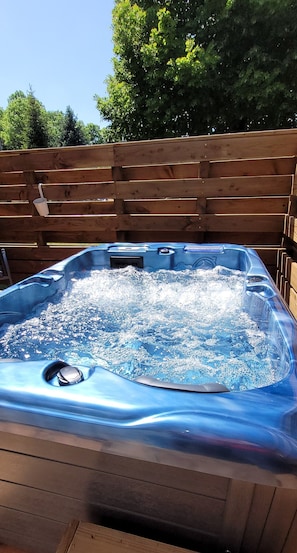 Un bain Ă remous rempli dâeau, entourĂ© dâune clĂŽture en bois.
