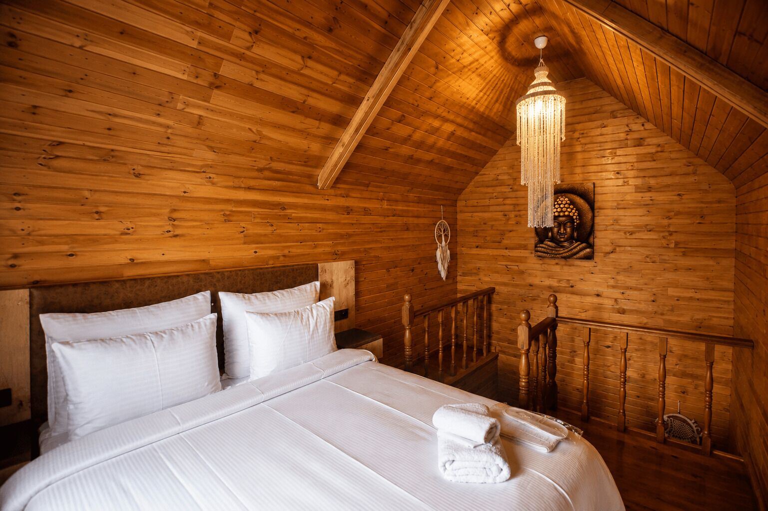 Une pièce en bois avec un lit, un lustre et une statue de Bouddha.