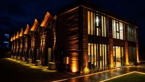 Un edificio moderno con varias habitaciones conectadas, ventanas amplias y un exterior bien iluminado.