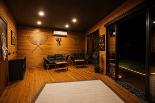 A cozy room with wooden walls, a sofa, a coffee table, and a potted plant.