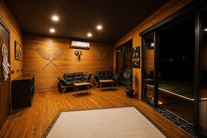 A cozy room with wooden walls, a sofa, a coffee table, and a potted plant.