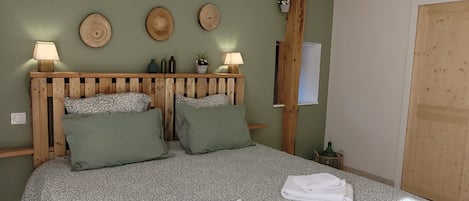 Une chambre à coucher avec une tête de lit en bois, deux lampes de chevet, un lit recouvert d’une couvre-lit à motifs et deux oreillers.