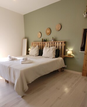 Habitación de hotel con cama, almohadas, mesita de noche con lámpara y estante en la pared.