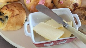 Un plateau de petit-déjeuner avec des muffins, un beurrier et un pichet de thé.