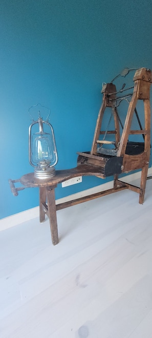 A wooden chair with a metal frame and a glass lantern on a white floor against a blue wall.