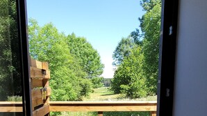 A view through a glass door to an outdoor wooden deck with a bench. - “Chambre Margeride” Guest Room with Private Terrace (Soulages)