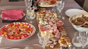 Una tavola apparecchiata per un pasto, con diversi cibi, bicchieri da vino e una bottiglia.