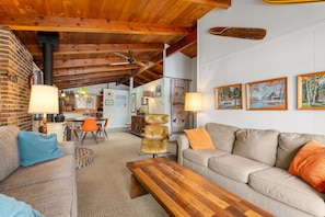 A cozy living room with a sofa, a wooden coffee table, a leather chair, and a dining area with a table and chairs.