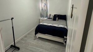 A bedroom with a bed, a window with curtains, a ceiling light, and a door. - Dagsboro Retreat (Dagsboro)