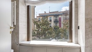 A bathroom with a window view of a building, a toilet, and a vanity with cabinets. - Exclusive Studio in Salamanca Isla de la Rua I (Salamanca)