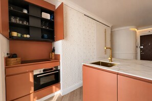 A modern kitchen with a built-in oven, a sink with a gold faucet, and a patterned backsplash. - Refined Apartment in Seville s Historic Centre General Casta os (Seville)